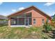 A view of the house's backyard with a screened patio, grass, and the exterior wall at 1803 Tillstream Dr, Orlando, FL 32818