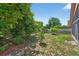 Backyard view featuring green grass, trees, plants, and a partial view of the home at 1803 Tillstream Dr, Orlando, FL 32818