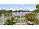 A serene view of the lake from the backyard, framed by vibrant flowers and a charming white picket fence at 2076 Shannon Lakes Blvd, Kissimmee, FL 34743
