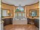 Luxurious bathroom with a standalone tub beneath an arched window and dual vanities with granite countertops at 3619 King George Dr, Orlando, FL 32835