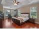 Spacious main bedroom with tray ceilings, wood floors, abundant natural light, and a cozy seating area at 3619 King George Dr, Orlando, FL 32835