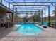 Spacious, screened pool area with lounge chairs, outdoor kitchen and verdant landscaping at 3619 King George Dr, Orlando, FL 32835