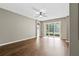 Spacious living room featuring wood flooring, neutral paint, fan, and sliding glass door to backyard at 413 Pursley Dr, Deland, FL 32724