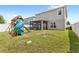 Fenced backyard featuring a wooden playset with a slide, a screened-in patio, and a spacious lawn at 4301 Creek Bank Dr, Kissimmee, FL 34744