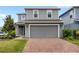 Two-story gray home featuring a brick-paved driveway, lawn, and garage door at 4301 Creek Bank Dr, Kissimmee, FL 34744