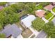 Aerial view of a home with a screened pool, white roof, surrounded by lush trees in a residential neighborhood at 452 Sundown Trl, Casselberry, FL 32707