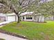 Quaint home with a lush lawn, stone-lined flower beds, and large oak tree at 452 Sundown Trl, Casselberry, FL 32707