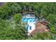 Aerial view of a community pool with blue umbrellas and lounge chairs surrounded by lush trees at 5259 Images Cir # 301, Kissimmee, FL 34746