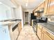Kitchen featuring light wood cabinets, stainless steel appliances, granite counters, and tile floors at 5500 Devonbriar Way # 202, Orlando, FL 32822