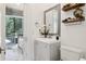 Bright bathroom with a gray wood vanity, floral accents and views out to the spiral staircase at 621 Estates Pl, Longwood, FL 32779