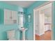 Bright blue bathroom with pedestal sink and doorway looking to the kitchen at 628 Olympic Dr # 8-C, Ocoee, FL 34761