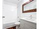 Bright bathroom featuring a tiled shower-tub combo, stylish vanity, and decorative wood-trimmed mirror at 709 Orchid Dr, Davenport, FL 33897