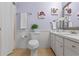 Well-lit bathroom featuring a vanity with drawers, decorative art, and a toilet with plants at 73 Alano Rd, Debary, FL 32713