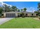 Charming single Gathering house featuring a lush green lawn, paved driveway, and a spacious two-car garage at 73 Alano Rd, Debary, FL 32713