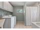 Well-lit laundry room featuring a washer, dryer, wash tub, cabinets, and shower at 73 Alano Rd, Debary, FL 32713