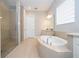 Bright bathroom featuring a soaking tub, tile floors, and a separate tiled shower stall with glass door at 7388 John Hancock Dr, Winter Garden, FL 34787