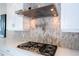 Modern cooktop with stainless steel range hood, pot filler, and granite backsplash at 7388 John Hancock Dr, Winter Garden, FL 34787
