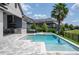 Backyard pool with an outdoor kitchen, patio seating, lush landscaping and lake views at 7388 John Hancock Dr, Winter Garden, FL 34787