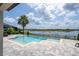 Stunning pool area with a lake view, a palm tree, and a tiled patio under a blue sky at 7388 John Hancock Dr, Winter Garden, FL 34787
