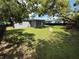Green backyard featuring a grey house, walkway, and mature trees at 7709 Ravenna Ave, Orlando, FL 32819
