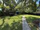 Expansive backyard featuring lush greenery, a paved pathway, and a mature shade tree at 7709 Ravenna Ave, Orlando, FL 32819