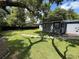 Spacious backyard with lush grass, grey house, and shady trees at 7709 Ravenna Ave, Orlando, FL 32819