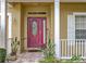 Close-up of a red front door, side panel window, white porch railing and cream colored exterior at 7939 Riffle Ln, Orlando, FL 32818