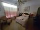 A bedroom with a floral patterned queen bed, a ceiling fan and a window with shear curtains at 8603 Snowfire Dr, Orlando, FL 32818