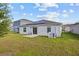 View of a spacious backyard with a simple patio, featuring solar panels on the rear of the home at 873 Daring Dr, Davenport, FL 33837