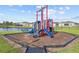 Community playground with a blue slide, climbing structure, and a bench overlooking the pond at 873 Daring Dr, Davenport, FL 33837