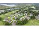 Bird's eye view showing residential homes nestled within a golf community, featuring tennis courts and a scenic lake at 8932 Village Green Blvd, Clermont, FL 34711