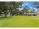 Expansive backyard with lush green grass and mature trees providing shade and privacy at 8932 Village Green Blvd, Clermont, FL 34711