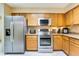 Kitchen featuring stainless steel appliances, granite countertops, and wood cabinetry at 8932 Village Green Blvd, Clermont, FL 34711