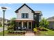 Charming two-story home with a welcoming front porch, lush landscaping, and elegant black and white exterior at 9201 Smithies St, Orlando, FL 32827
