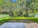 Spacious backyard with green grass, lush trees, and a white fence for privacy at 9454 Candice Ct, Orlando, FL 32832