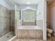 Bathroom with tile shower, bathtub, and large window providing natural light and green view at 9454 Candice Ct, Orlando, FL 32832