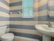 Unique half-bathroom with blue and tan stripes and a pedestal sink under a window at 9454 Candice Ct, Orlando, FL 32832