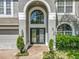 Close-up of a home's front entrance, showcasing the arched entryway, double doors, and manicured landscaping at 9454 Candice Ct, Orlando, FL 32832