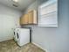 Bright laundry room with a side-by-side washer and dryer, window, and overhead cabinets at 9454 Candice Ct, Orlando, FL 32832