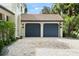 Two-car garage featuring blue doors, a red tile roof, and lush tropical landscaping at 9809 Covent Garden Dr # Drive, Orlando, FL 32827