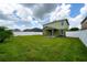 A large backyard featuring a green lawn, a perimeter privacy fence, and a covered outdoor patio at 1951 Betsy Ross Ln, St Cloud, FL 34769