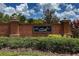 Well-maintained brick community entrance featuring lush landscaping and signage on a sunny day at 1951 Betsy Ross Ln, St Cloud, FL 34769