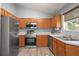 Functional kitchen featuring stainless steel appliances, wooden cabinets, and a window view of the outdoors at 10473 Glassborough Dr, Orlando, FL 32825