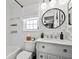 Elegant bathroom with marble countertop vanity, round mirror, and tub with tiled walls, complemented by modern lighting at 1100 E Caroline St # 204, Tavares, FL 32778