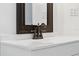 Close up of a vanity in a bathroom with bronze fixtures and a framed mirror at 121 W Oakland Ave, Oakland, FL 34760