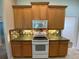 Cozy kitchen featuring wood cabinetry, a white range, and a tile backsplash at 1227 Juniper Hammock St, Winter Garden, FL 34787