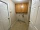 A simple laundry room with tile flooring and wooden cabinets above the hookups at 1227 Juniper Hammock St, Winter Garden, FL 34787