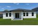 The home's rear exterior showcases a sleek modern design, expansive windows, and a covered patio at 1309 Hillsborough Ln, Kissimmee, FL 34759