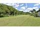 Expansive backyard with lush green lawn and mature palm trees under a blue, partly cloudy sky at 1390 E Airport Blvd, Sanford, FL 32773