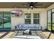 This covered patio features a ceiling fan, comfortable seating, and a TV for outdoor entertainment at 13924 Jomatt Loop, Winter Garden, FL 34787